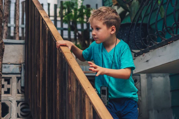 Salin gaya hidup ruang kecil anak laki-laki bergerak menaiki tangga kayu ke bawah luar memegang pegangan pegangan pegangan, mencari ekspresi wajah, bermain petak umpet, Konsep hati-hati mencari harapan baru, pendidikan anak-anak barang — Stok Foto