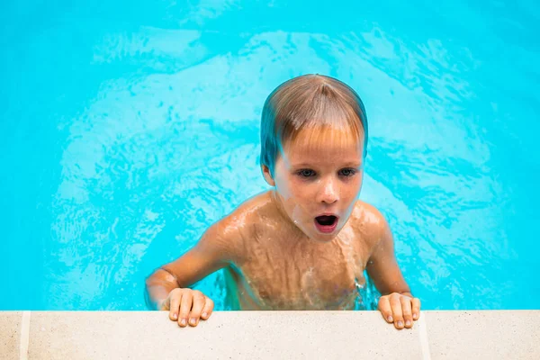 Lifestyle muotokuva vakava poika uida uima-altaassa, kun kova juna väsynyt, ilmestyy reunalla pitoon, kirkas sininen vesi. Kasvojen ilme, pisarat valuvat alas. Lapsuus, akvaarion kesäleirin vapaa-ajan toiminta — kuvapankkivalokuva