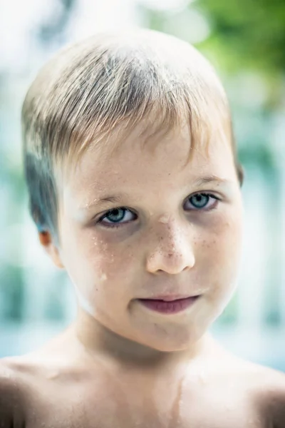 VERTIKAI Közelkép életmód portré huligán fiú néz kamera, elhanyagolja intrika mosoly arckifejezés. Uszodavíz cseppek arcbőrre, nedves haj. Gyermek viselkedés nevelés fia nehéz gyermek — Stock Fotó