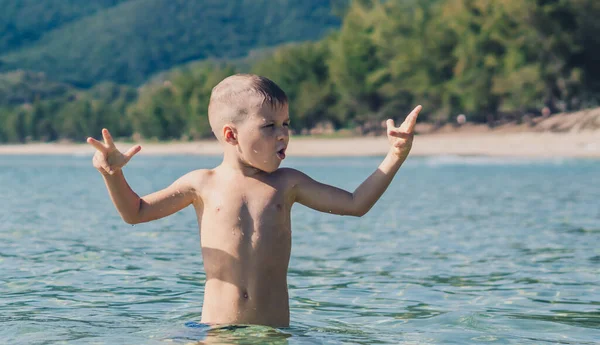 BANNER elämäntapa varastossa kuva poika uida tehdä liike ilonpito hauskaa roiskeita vettä mereen. Kesällä aurinko luonto maisema. Onnellinen lapsuus, matka loma lasten kanssa, vapaa-ajan toiminta, yksinkertainen hauska käyttäytyminen — kuvapankkivalokuva