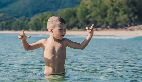 BANNER elämäntapa varastossa kuva poika uida tehdä liike ilonpito hauskaa roiskeita vettä mereen. Kesällä aurinko luonto maisema. Onnellinen lapsuus, matka loma lasten kanssa, vapaa-ajan toiminta, yksinkertainen hauska käyttäytyminen — kuvapankkivalokuva