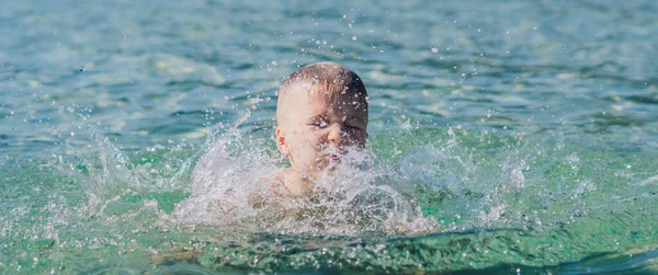 BANNER životní styl stock fotografie chlapec plavat dělat pohyb frolics zábava stříkající vody moře. Letní slunce krajina přírody. Šťastné dětství, cestovní dovolená s dětmi, volnočasová aktivita, jednoduché zábavné chování — Stock fotografie