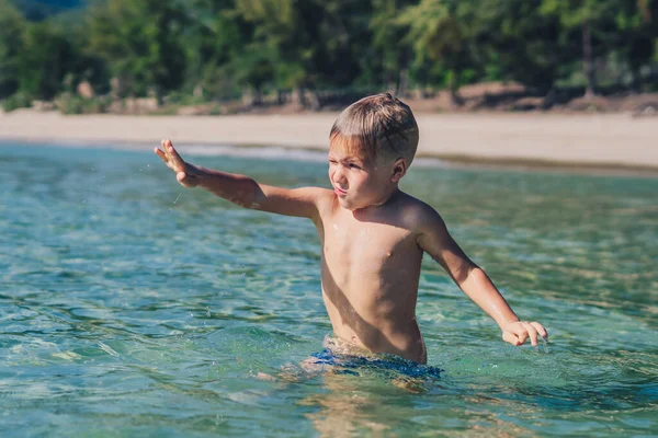 Lifestyle stoc fotografie băiat înot face mișcare frolics distracție stropire apă mare. Vara soare natura peisaj. Copilărie fericită, vacanță de călătorie cu copii, activitate de agrement, comportament distractiv simplu — Fotografie, imagine de stoc