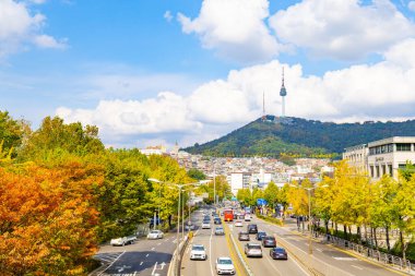 Güney Kore, Seul 'de sonbahar yeşilliklerini, şehir trafiğini ve Namsan Seul Kulesi' ni gösteren editör görüntüleri, 25 Ekim 2025 'te, dağınık mavi bulutların altında çekildi.
