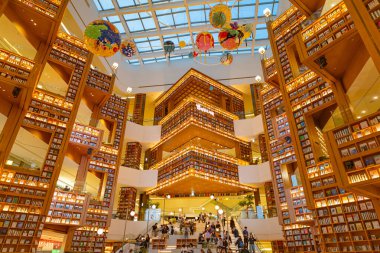 Güney Kore, Seul 'deki Starfield Kütüphanesi' nde 25 Ekim 2025 'te uzun aydınlatılmış kitap rafları ve çeşitli okuma alanlarının yer aldığı ziyaretçileri gösteren editör görüntüleri.