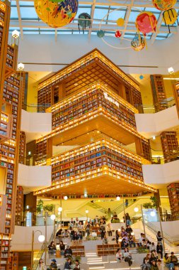 Yayın görüntüsü, Güney Kore 'deki Starfield Kütüphanesi' nde 25 Ekim 2025 'te aydınlatılmış kitaplıklar ve asılı süslemelerle yakalanan ziyaretçileri okuma ve rahatlama basamaklarında gösteriyor.