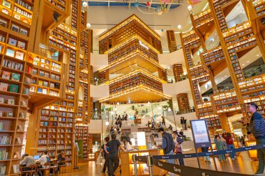 25 Ekim 2025 'te Güney Kore, Seul' deki Starfield Kütüphanesi 'nin kapalı atmosferini çeken editör görüntüsü, ziyaretçilerin aydınlatılmış basamaklar boyunca oturması ve kitap raflarıyla çevrelenmiş olması.