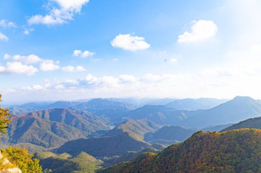 Daedunsan 'da açık gün ışığında kayan yüksek açılı dağlar ve yumuşak bulutların yakalandığı manzaralı bir manzara.