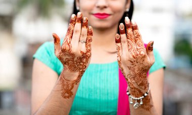 Portrait of a young Indian woman in casual style with mehendi or henna design on the both hands clipart