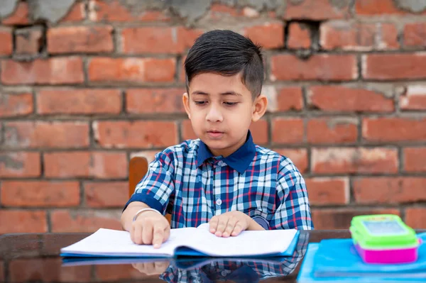 Primary school student in proper school uniform reading book on study table in classroom. Indian education system in Primary school.