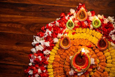 Diwali kutlaması - Diya yağ lambaları ahşap arka planda renkli rangoli çiçeklere ışık tutuyor
