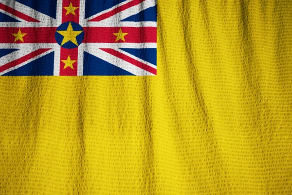 Primer plano de la bandera de Niue con volantes, bandera de Niue soplando en el viento — Foto de Stock