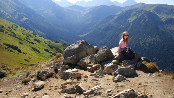 Girl sitting on a rock and looking at the landscape. She's tired. — Stock Photo, Image