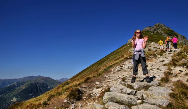 Menina feliz andando nas montanhas. Ela está a sorrir . — Fotografia de Stock