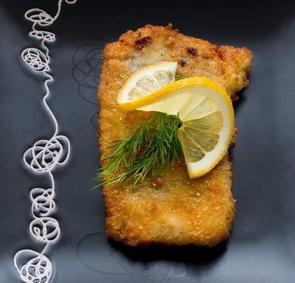 Christmas, fried carp with lemon on black plate — Stock Photo, Image