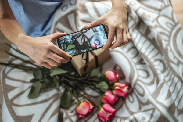 Жінка Тримає Мобільний Телефон Фотографує Квіти Подарункову Коробку Ліжку Концепція — стокове фото