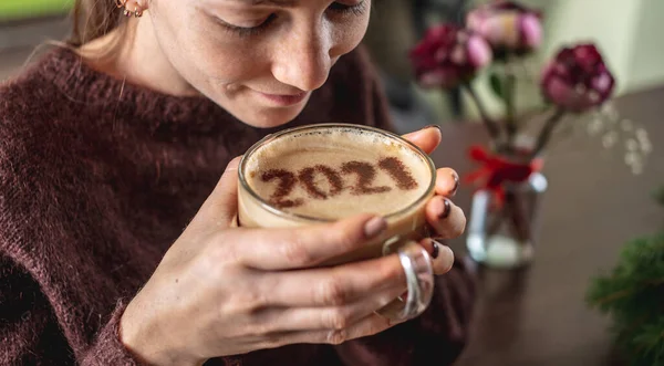 居心地の良い暖かいセーターを着た若い女性が熱いコーヒーを楽しんでいます ミルクフォームには2021の番号があります 新年のコンセプト — ストック写真