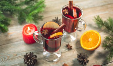 Tarçınlı sıcak şarap, yıldız anason ve ahşap bir masada meyve ile süslenmiş birkaç cam bardak. Geleneksel sıcak kış içeceği kavramı.