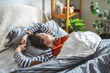 Sevimli mutlu genç kız uyuyor ve güneşli bir sabah uyanıyor ve rahat yatağında. Güne iyi bir şekilde başlamanın kavramı..