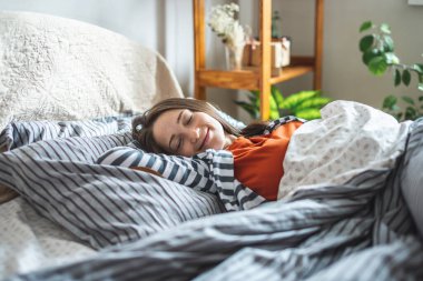 Sevimli mutlu genç kız uyuyor ve güneşli bir sabah uyanıyor ve rahat yatağında. Güne iyi bir şekilde başlamanın kavramı..