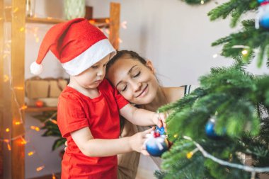Anne ve küçük oğlu Noel ağacını oyuncaklar ve Noel toplarıyla süslüyorlar. Yeni yıl arifesinde mutlu ve sevgi dolu bir aile kavramı