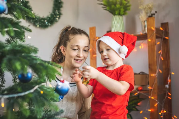 Anne ve küçük oğlu Noel ağacını oyuncaklar ve Noel toplarıyla süslüyorlar. Yeni yıl arifesinde mutlu ve sevgi dolu bir aile kavramı