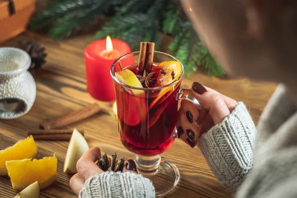 暖かいセーターの女性は 木製のテーブルの上に彼女の手の中に芳香族ホットホットマルワインのカップを保持しています お祝いと居心地の良い雰囲気の概念 — ストック写真