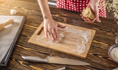 Kadın, mutfağında ev yapımı zencefilli kurabiye yaptığı için elinde çiğ hamur tutuyor..