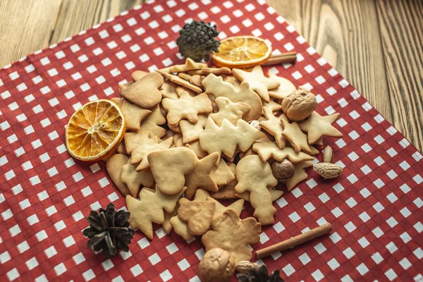 stock image A heap of delicious shaped homemade cookies on a red tablecloth on a wooden table. Concept of fresh homemade cakes and a cozy atmosphere.