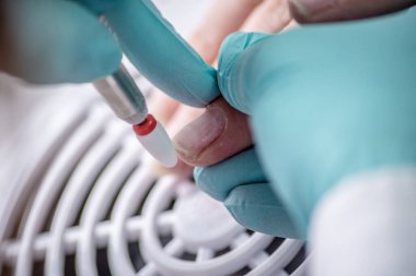 Usta, manikür makinesi kullanarak müşterinin tırnaklarıyla uğraşıyor. Profesyonel manikür yapma, el bakımı ve hasarlı tırnakların restorasyonu süreci kavramı. Yakın çekim.