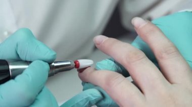Usta, bir tırnak matkabıyla müşterilerin tırnaklarındaki jel cilasını çıkarıyor. Profesyonel manikür yapma süreci kavramı