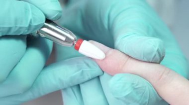 Usta, bir tırnak matkabıyla müşterilerin tırnaklarındaki jel cilasını çıkarıyor. Profesyonel manikür yapma süreci kavramı