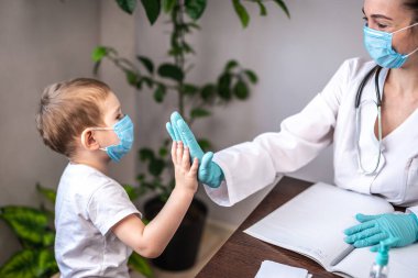 Küçük bir hasta çocuk doktorunu ziyaret ediyor ve doktora beşlik çakıyor. Doktorun muayenesinde dostane atmosfer kavramı.