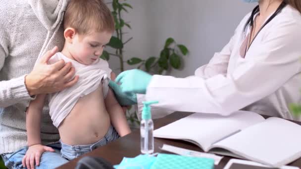 Eine junge Ärztin misst mit einem elektronischen Thermometer die Temperatur eines kleinen Jungen — Stockvideo