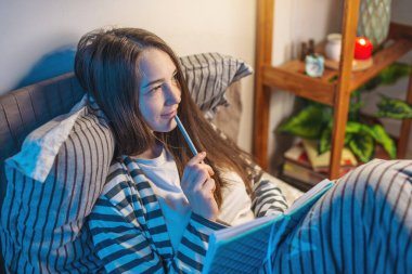 Yatmadan önce yatağında yatan genç bir kadın bir günlük ya da not defteri yazıyor. Uyku zamanı eğlencesi, ritüeller ve gece hayatı kavramı.