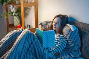 Yatmadan önce yatağında yatan genç bir kadın bir günlük ya da not defteri yazıyor. Uyku zamanı eğlencesi, ritüeller ve gece hayatı kavramı.