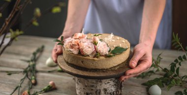 Kadın elinde şefkat çiçekleriyle süslenmiş güzel bir kremalı pasta tutuyor. Romantik atmosfer ve bahar havası kavramı.