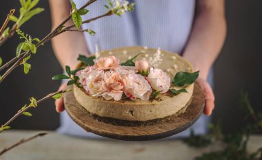 Kadın elinde şefkat çiçekleriyle süslenmiş güzel bir kremalı pasta tutuyor. Romantik atmosfer ve bahar havası kavramı.