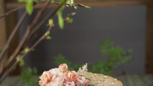 Decoradores mano está decorando un delicioso pastel de mousse crudo con flores de color rosa ternura y hojas verdes. Concepto de ambiente romántico y atmósfera primaveral — Vídeos de Stock