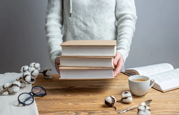 Woman is holding a stack of books wrapped in craft paper. Concept of reading, choosing a book and celebrating World Book Day.