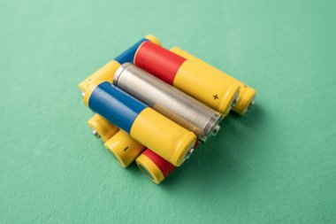 Yeşil arka planda bir yığın pil. Kullanılan pillerin geri dönüşümü, çevre kirliliği ve çevre dostu davranış.