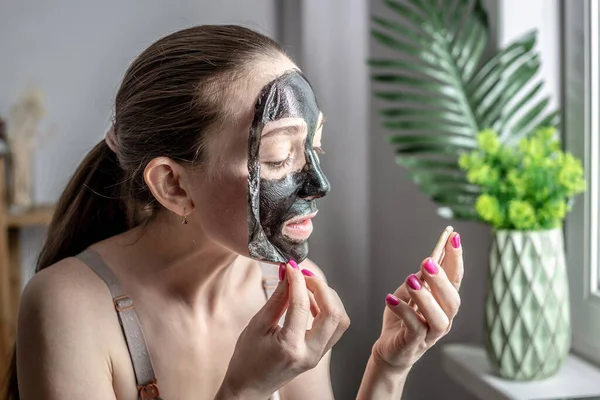 Egy Fiatal Tükröt Tart Kezében Leveszi Kozmetikai Fekete Maszkot Arcáról — Stock Fotó