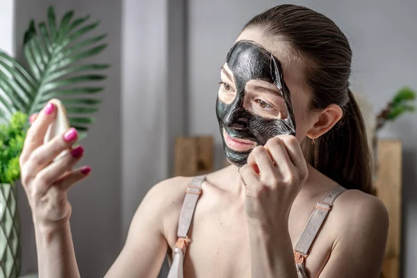 Fiatal Gyönyörű Tükröt Tart Kezében Leveszi Kozmetikai Fekete Maszkot Arcáról — Stock Fotó