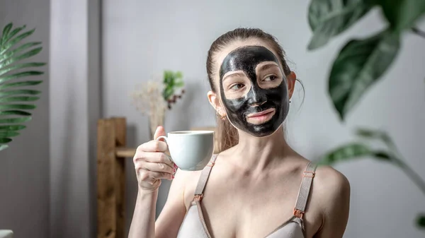 Mujer Joven Una Mascarilla Natural Carbón Negro Con Taza Café — Foto de Stock