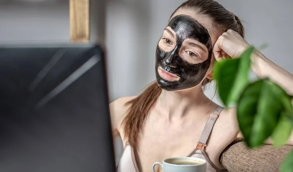 Egy Fiatal Kozmetikai Fekete Maszkkal Arcán Egy Csésze Kávé Laptopot — Stock Fotó