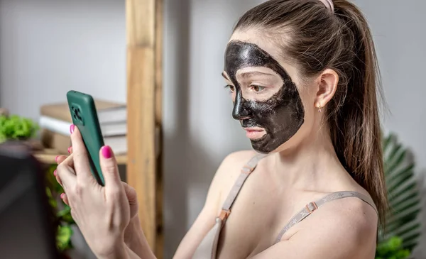 Jonge Vrouw Met Een Cosmetisch Zwart Masker Haar Gezicht Gebruikt — Stockfoto