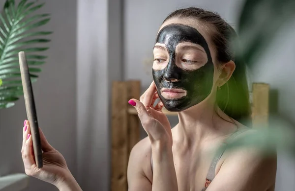 Een Jonge Vrouw Heeft Een Cosmetisch Zwart Masker Haar Gezicht — Stockfoto