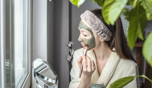 Jonge Mooie Vrouw Een Badjas Brengt Een Groen Cosmetisch Masker — Stockfoto