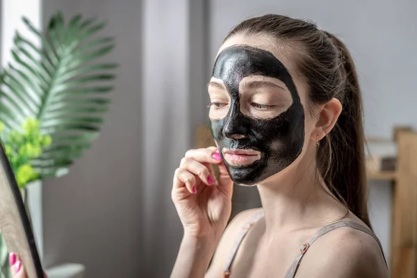 Een Jonge Vrouw Heeft Een Cosmetisch Zwart Masker Haar Gezicht — Stockfoto