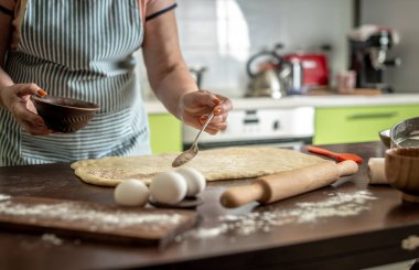 Kadın ev yapımı çörekler yapmak için çiğ hamura tarçın serpiyor. Pişirme süreci kavramı.